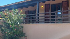 Ein Gebäude mit Balkon, Holzläden und einer Lampe.