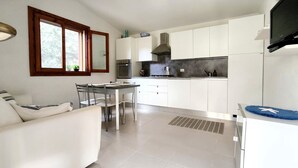 Eine moderne Küche mit weißen Schränken, einem Essbereich mit Tisch und Stühlen sowie einem eingebauten Backofen.