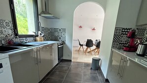 Eine moderne Küche mit einer zentralen Kochinsel, einem Essbereich mit Stühlen und einem Blick durch einen Bogen auf einen Esstisch.