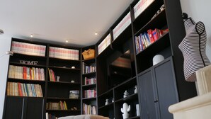 Eine gemütliche Leseecke mit einem großen Bücherregal voller Bücher, einem bequemen Sessel und einem kleinen Tisch.