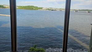 Vista a través de una ventana que muestra una masa de agua con un puente a lo lejos.