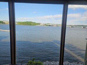 Une vue à travers une fenêtre sur une étendue d’eau, avec un pont visible au loin.
