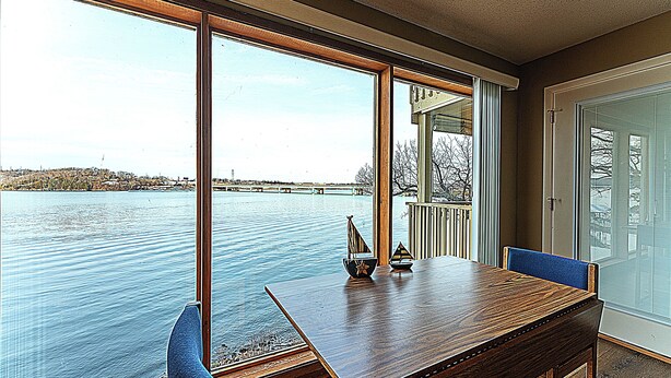 Una habitación con un ventanal grande que da a una masa de agua, una mesa de madera y una silla.