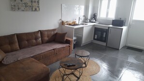 A compact living space with a brown sofa, a small round table, a kitchenette, and a window. - le spa d Ailly (Ailly-sur-Somme)