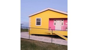 Un bâtiment jaune avec une porte rose et une fenêtre blanche.
