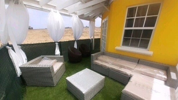 Un espace extérieur abrité, aménagé avec des meubles en osier et offrant une vue sur la plage.