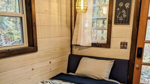 Ein gemütliches Schlafzimmer mit Bett, Holzwänden, einem Fenster und einer Tür.