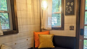 Ein gemütliches Blockhaus-Interieur mit einer eingebauten Sitzbank, einem kleinen Holztisch und einer Tür, die nach draußen führt.