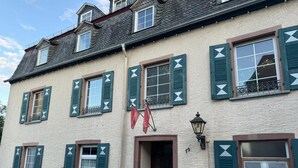 A traditional European building with multiple windows, green shutters, and a flag. - Schloss Hotel Kastellaun (Kastellaun)