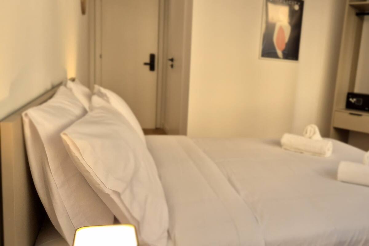 A hotel room with a bed, a TV, a desk, and a chair.
