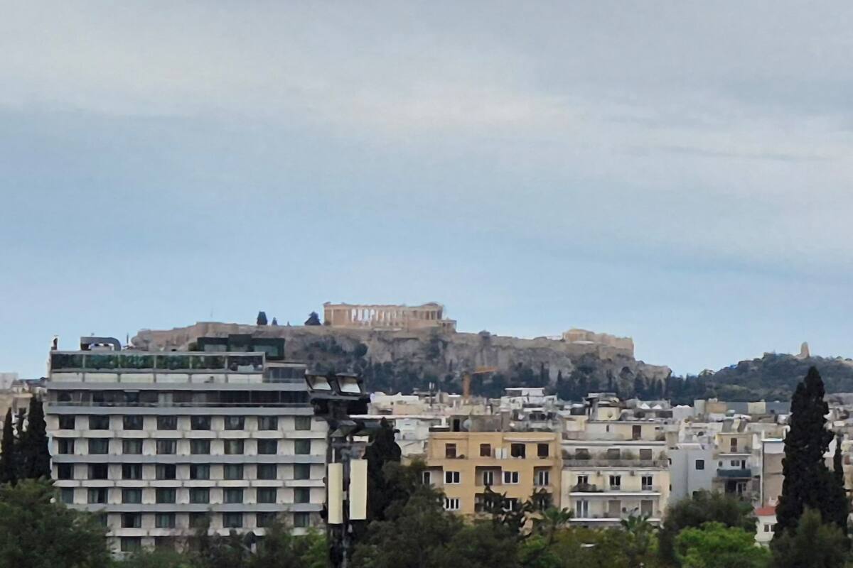 A cityscape with a prominent ancient fortress on a hill, surrounded by modern buildings.