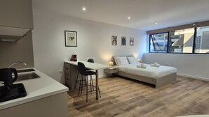 En moderne og kompakt bolig med tekøkken, seng og spiseplads.