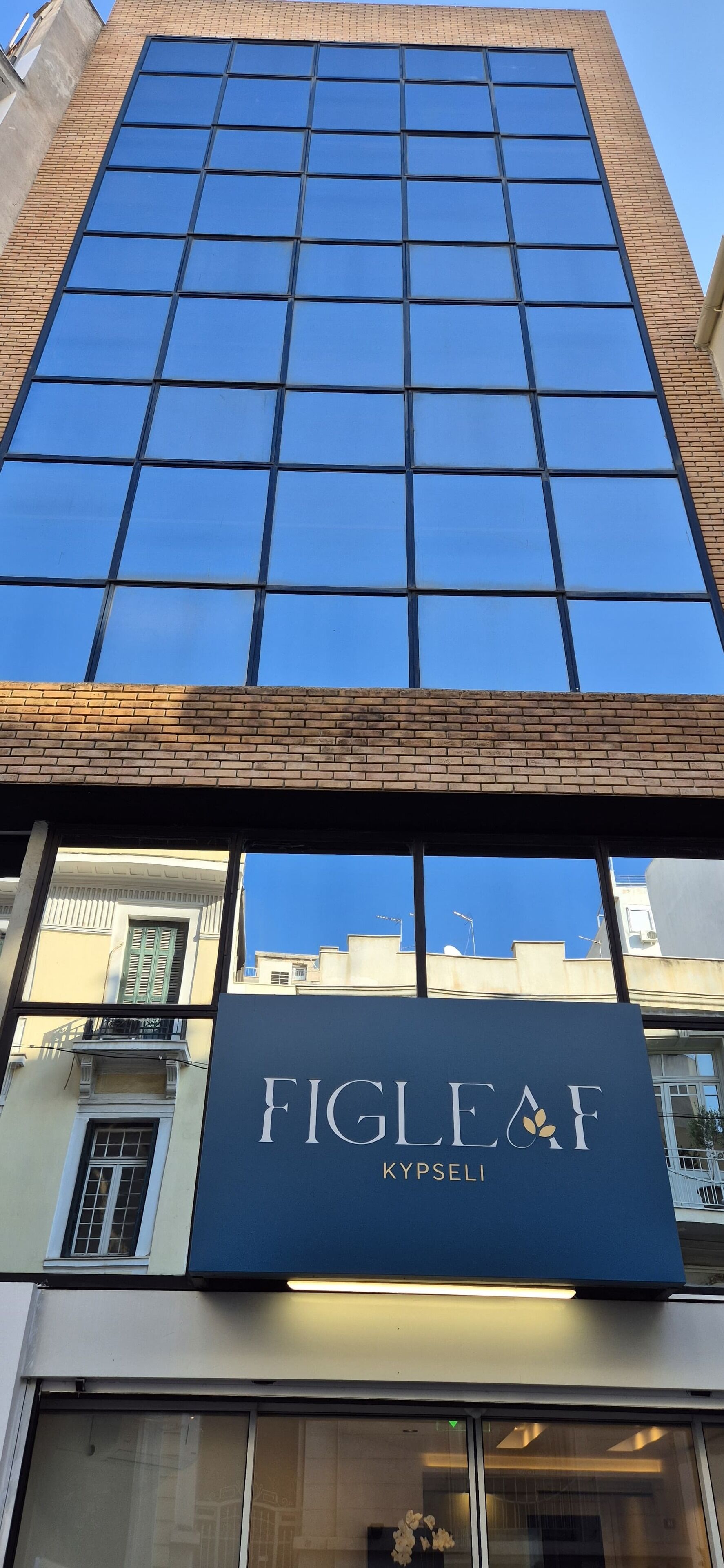 A building with a large glass facade and a sign for "FIGLEAF KYPSELI".