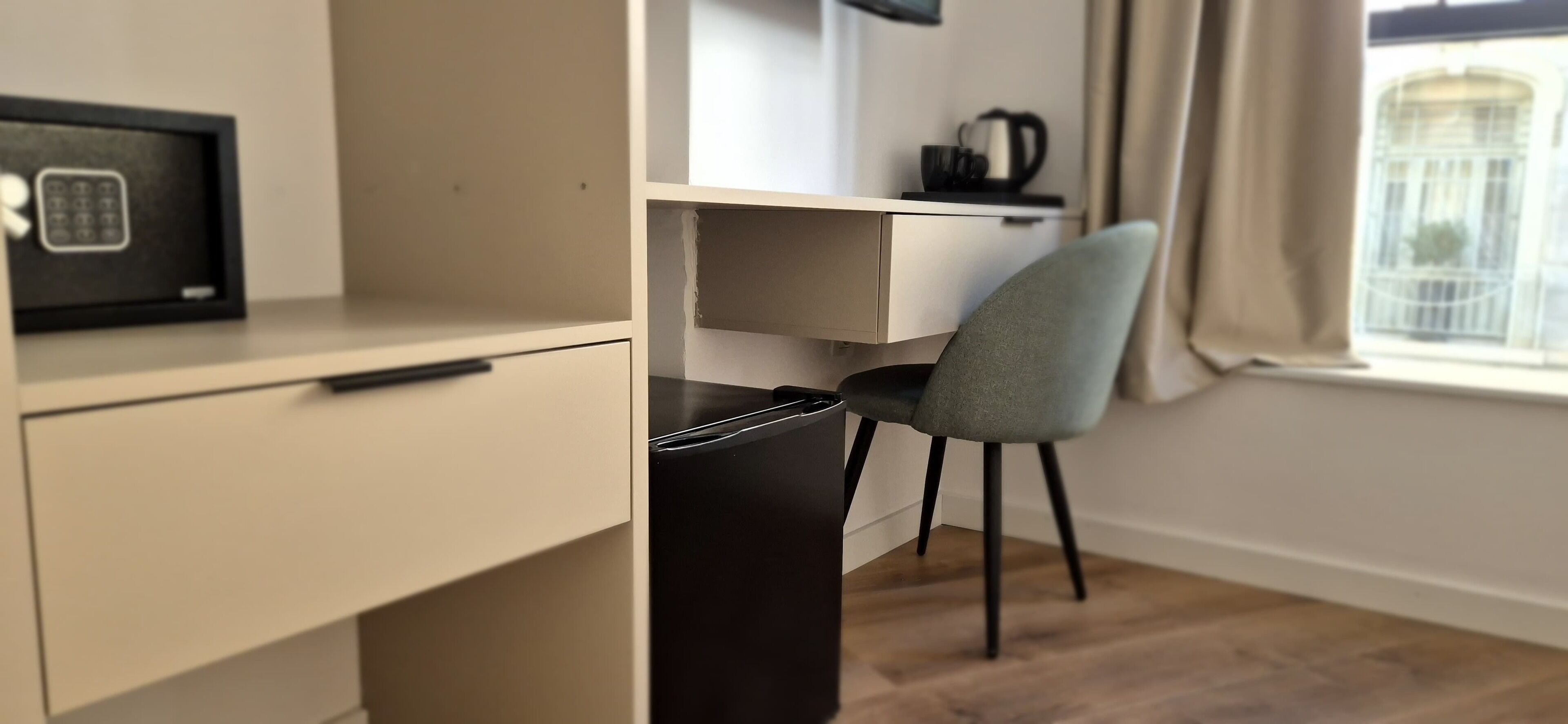 A modern, minimalist room with a desk, chair, and a safe.