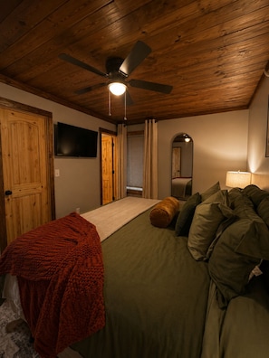 Una camera da letto con un letto, una ventola a soffitto, una TV e uno specchio.