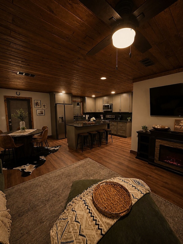 A modern kitchen with a central island, a dining area with a round table, and a cozy living space with a fireplace.