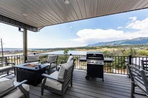 Enjoy al fresco dining with a view of the surrounding landscape from this outdoor deck, featuring a table, chairs, and barbecue grill.