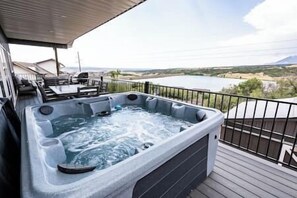 Relax on the deck overlooking the serene landscape, where a hot tub awaits with multiple jets and a cover.