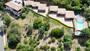 Vue aérienne d’un complexe hôtelier comprenant plusieurs villas, une piscine et une végétation luxuriante.