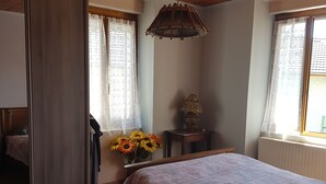 Una camera da letto con soffitto in legno, un letto con copripiumino floreale, un comodino, un tavolino con una lampada e uno specchio.