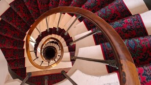 Un escalier en colimaçon avec une rampe en bois et une structure en verre.