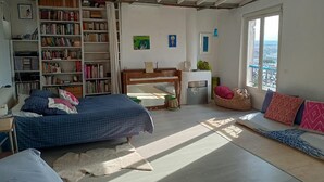Une chambre avec un lit, une bibliothèque, un bureau, une fenêtre et une vue sur la ville.