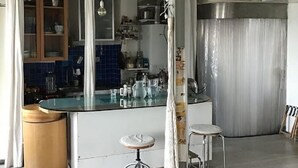 Une cuisine dotée d’un îlot central, de tabourets et d’un luminaire suspendu.