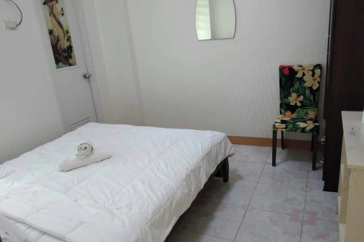 Un dormitorio con una cama, una silla y una mesita.