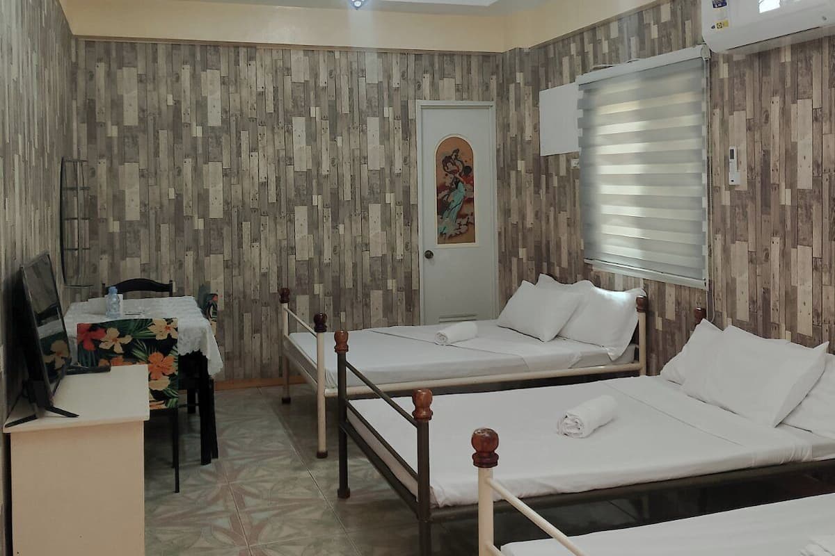 Habitación de hotel con dos camas individuales, un escritorio con silla, una mesita con otra silla y un cuadro decorativo en la pared.