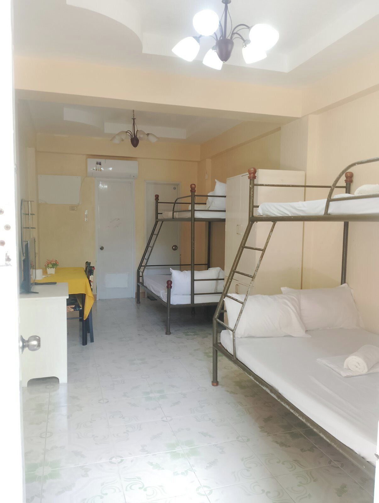 A dormitory room with bunk beds, a desk, and a chair.