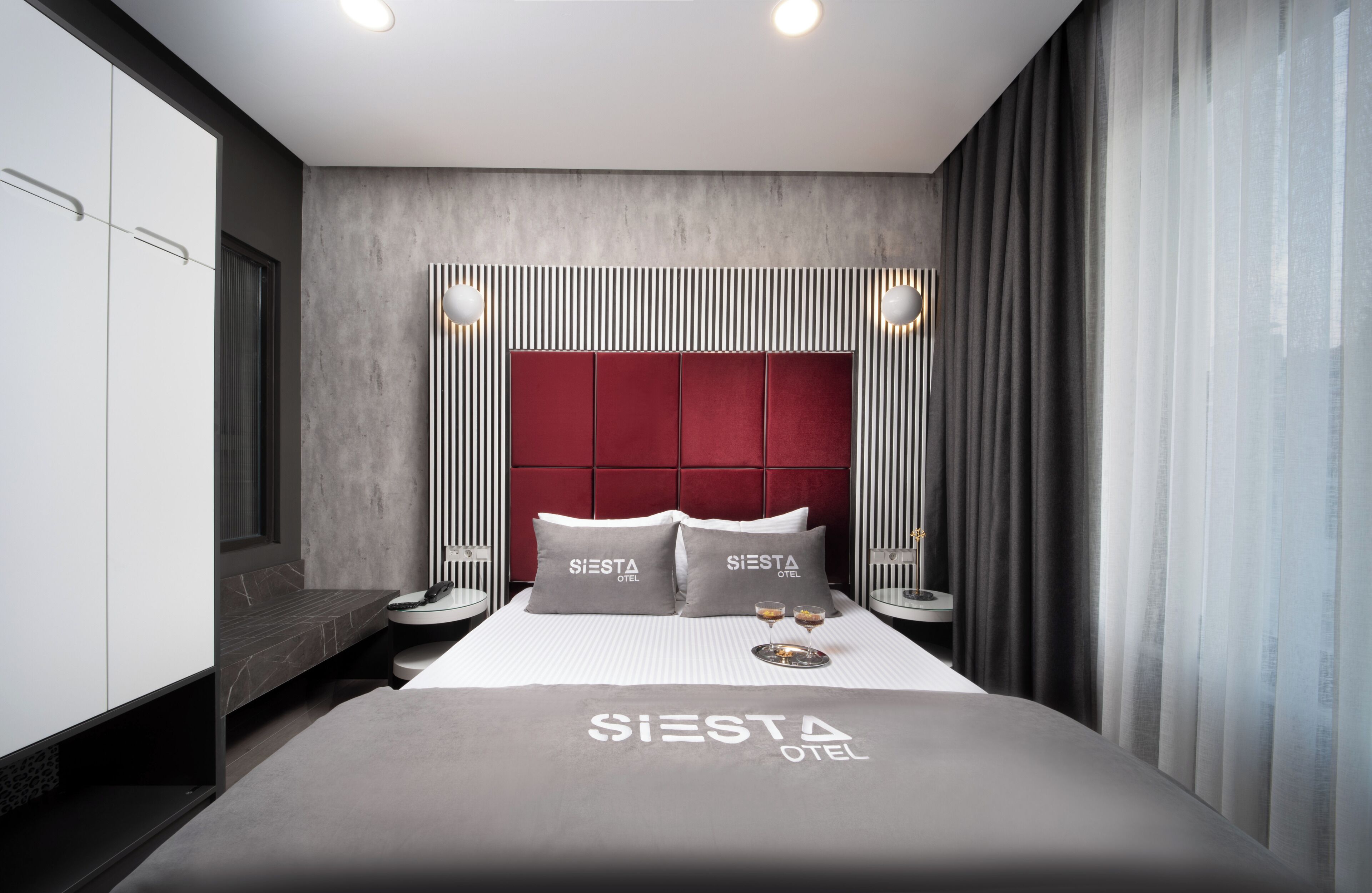 Ett modernt hotellrum med en stor säng, en röd sänggavel och en minibar.
