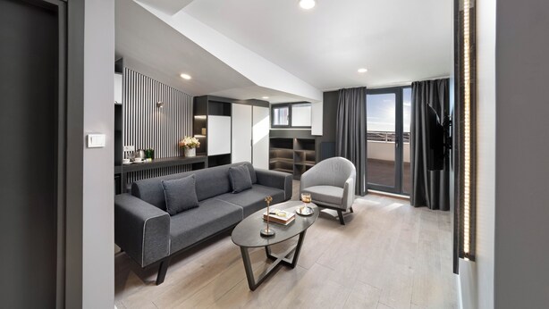 Een moderne woonkamer met een grijze bank, een ronde salontafel en een grijze fauteuil.
