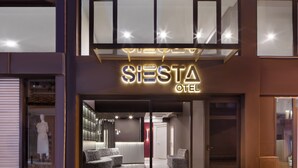 Een moderne hotelentree met een neonbord, een receptie en een zichtbare zithoek.