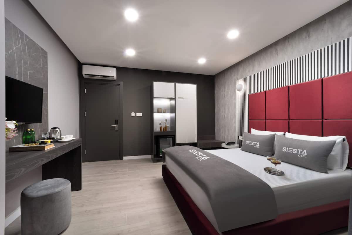 Una habitación de hotel moderna con una cama grande, un escritorio y un televisor.