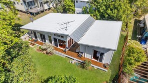 A modern two-story house with a large deck, a satellite dish, and a solar panel.