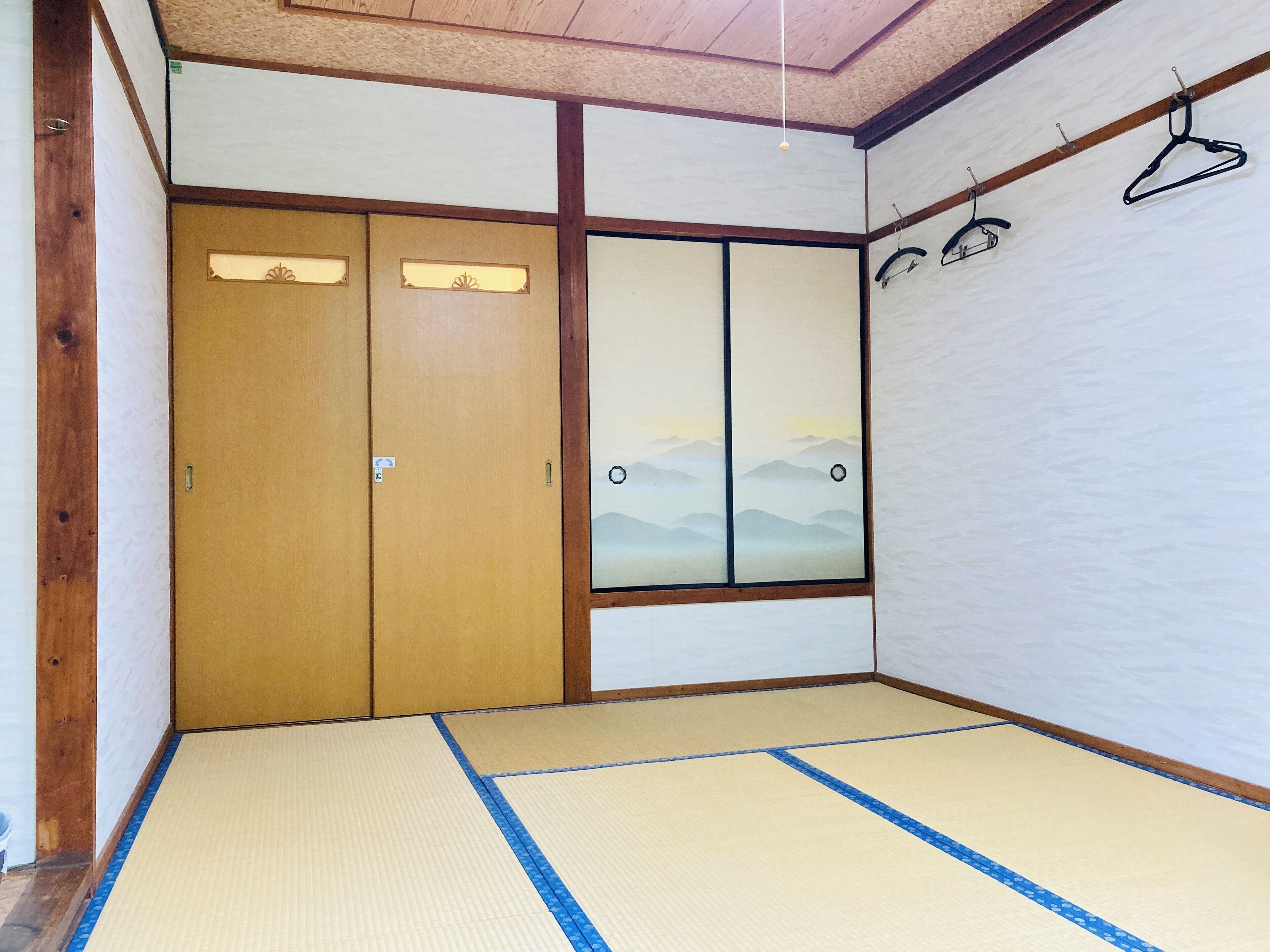 A traditional Japanese room with tatami flooring, sliding doors, and a view of mountains through a window.