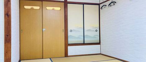 A traditional Japanese room with tatami flooring, sliding doors, and a view of mountains through a window.