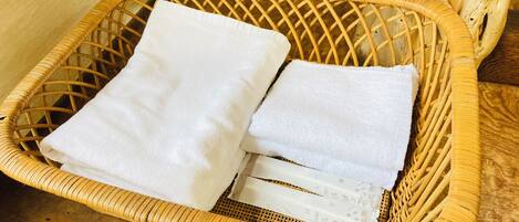 A wicker basket with folded white towels on a wooden floor.