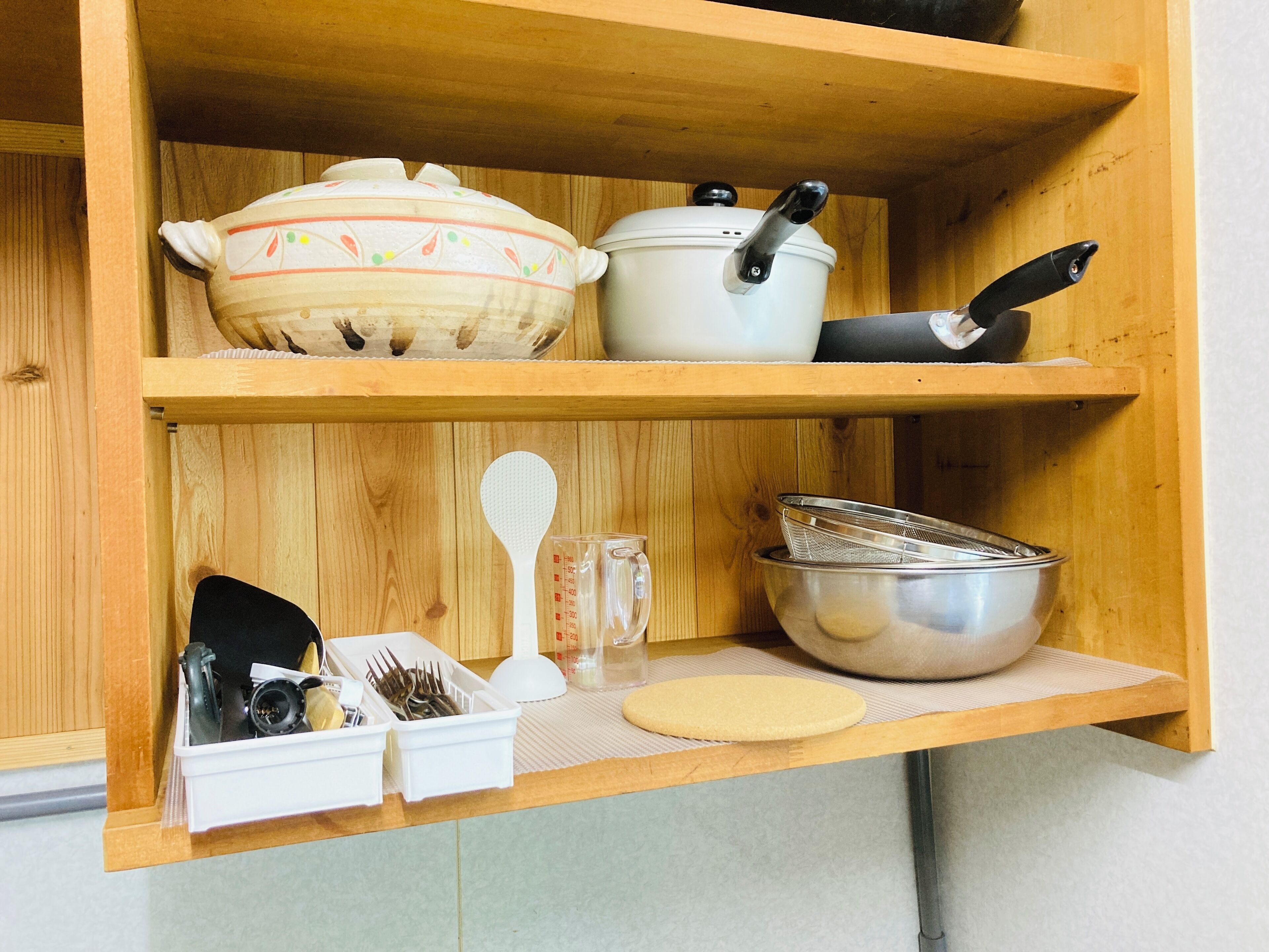 A kitchen shelf with various cooking utensils and cookware.