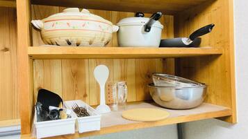 A kitchen shelf with various cooking utensils and cookware.