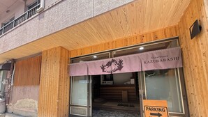 A guesthouse entrance with a wooden facade, a purple awning, and a parking sign indicating 70m ahead. - Guesthouse KAZURABASHI (Miyoshi)