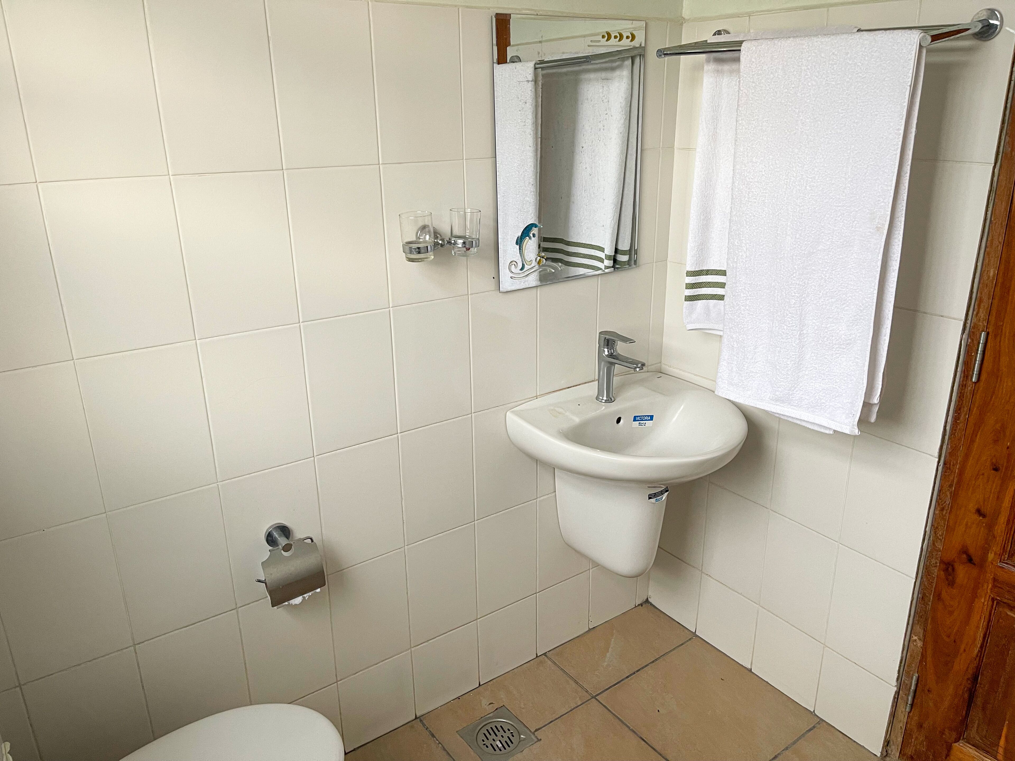 A bathroom with a white sink, mirror, and towel rack.