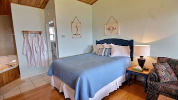 A bedroom with a bed, a nightstand, a lamp, a chair, and a wooden floor.