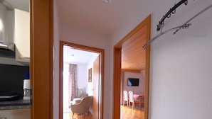 A hallway with a wooden floor, a dining area with chairs and a table, and a kitchen area with appliances. - Apartment, 55sqm with 8sqm balcony, 2-4persons in Baiersbronn center (Baiersbronn)