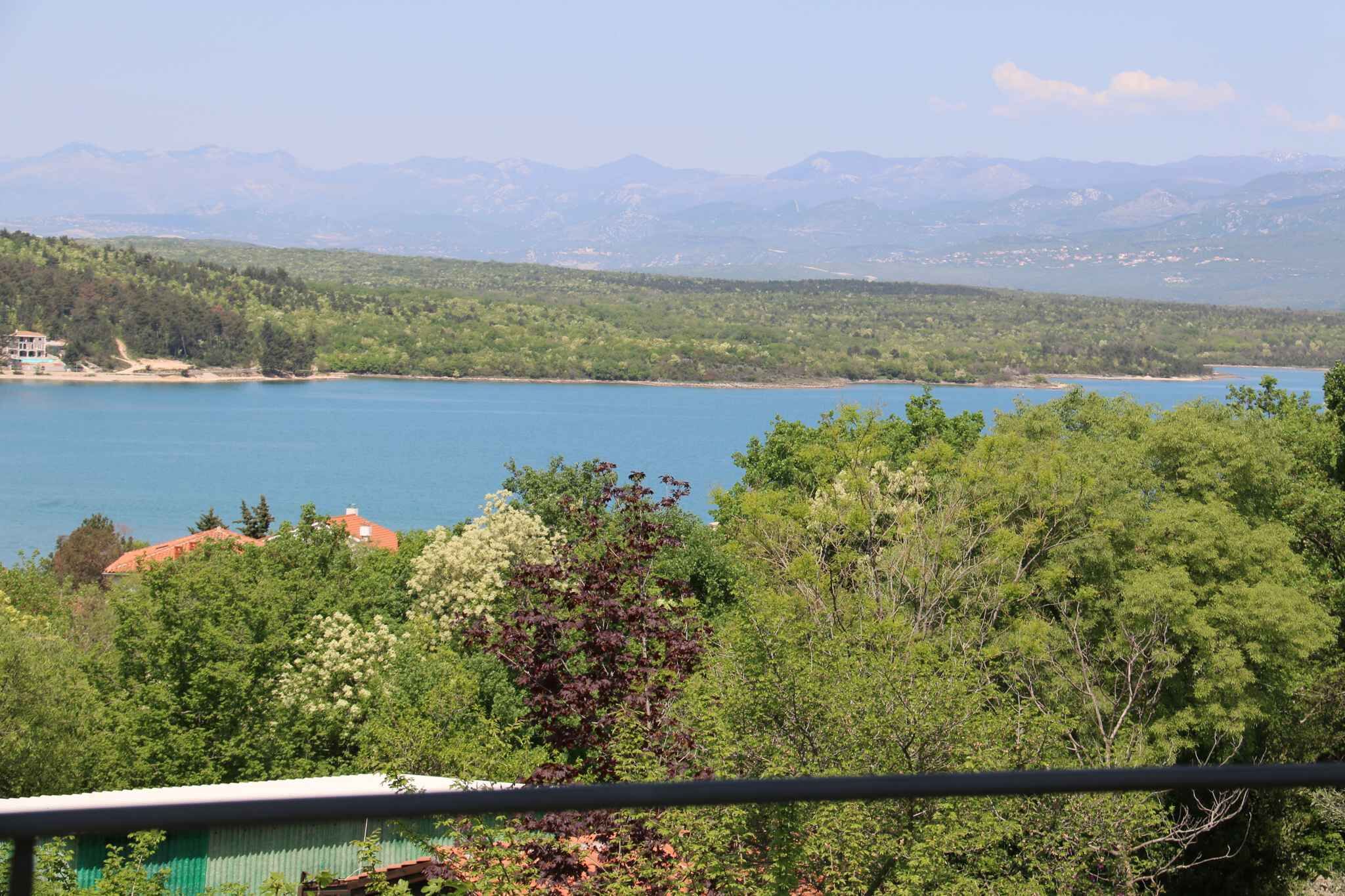 Vista de um lago rodeado por vegetação e montanhas.