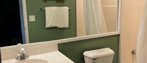 Un baño con lavamanos, inodoro y cortina de ducha.