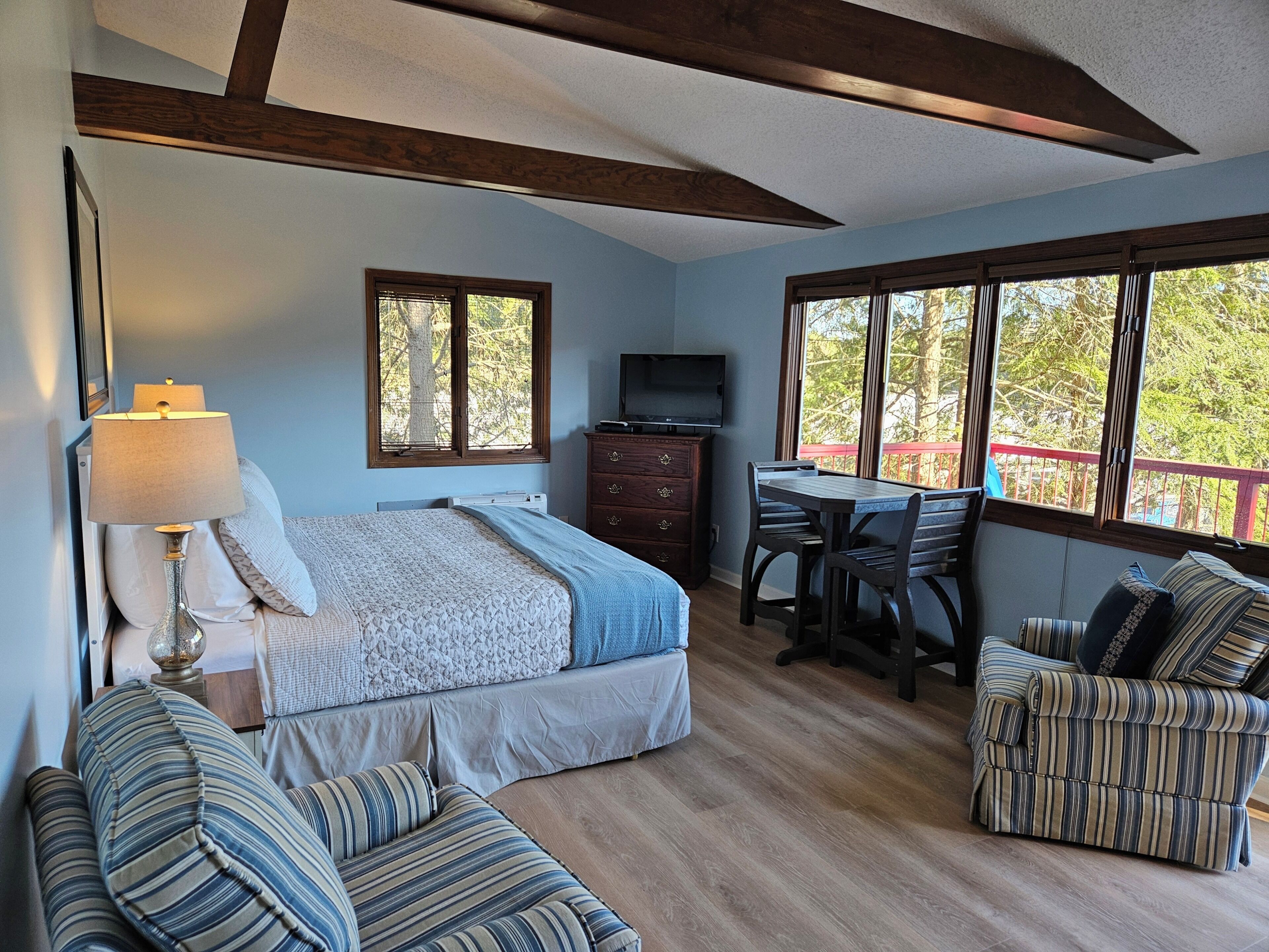 A bedroom with a bed, a desk, a TV, a chair, and a sofa.