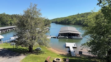 A lakeside dock with a covered boat ramp, a boat house, and a fire pit area.