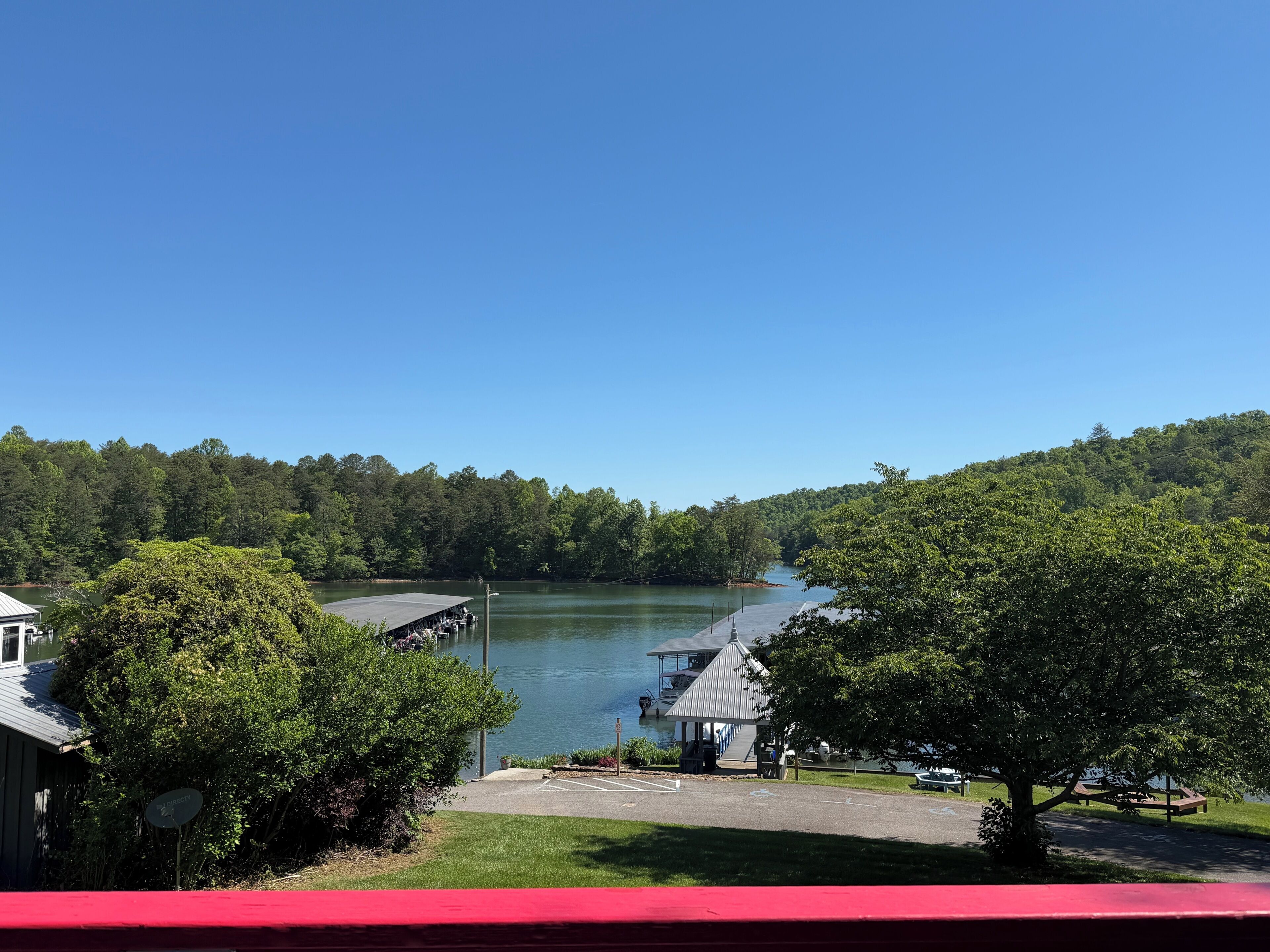 Vista para o lago com um cais, um pavilhão coberto e um estacionamento.