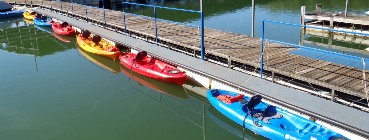 A row of kayaks docked at a pier with a wooden walkway.
